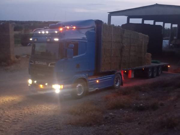 Camión cargado de pacas de paja al anochecer